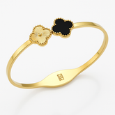 Gold bracelet with black clover-shaped charm on a white background