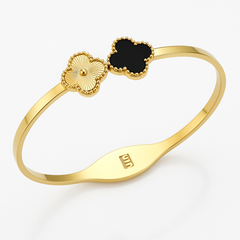 Gold bracelet with black clover-shaped charm on a white background