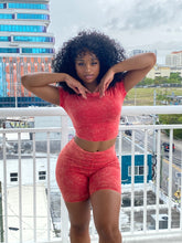 Woman wearing a red acid wash two-piece set featuring a fitted crop top and high-waisted biker shorts.