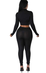 Woman wearing a sleek black full-length jumpsuit with long sleeves, side cutouts, and a sculpted corset-style bodice.