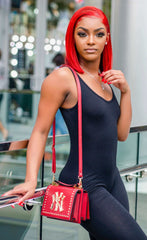 Woman in a sleek, sleeveless black fitted jumpsuit paired with a red crossbody purse.
