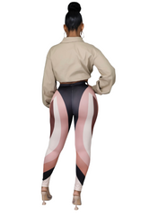 Woman wearing high-waisted leggings with a multicolor wave-pattern design in shades of black, blush, brown, and cream.