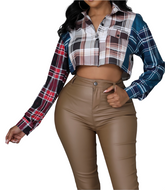 Woman wearing a multicolor plaid cropped button-up shirt with long sleeves and chest pocket detail.