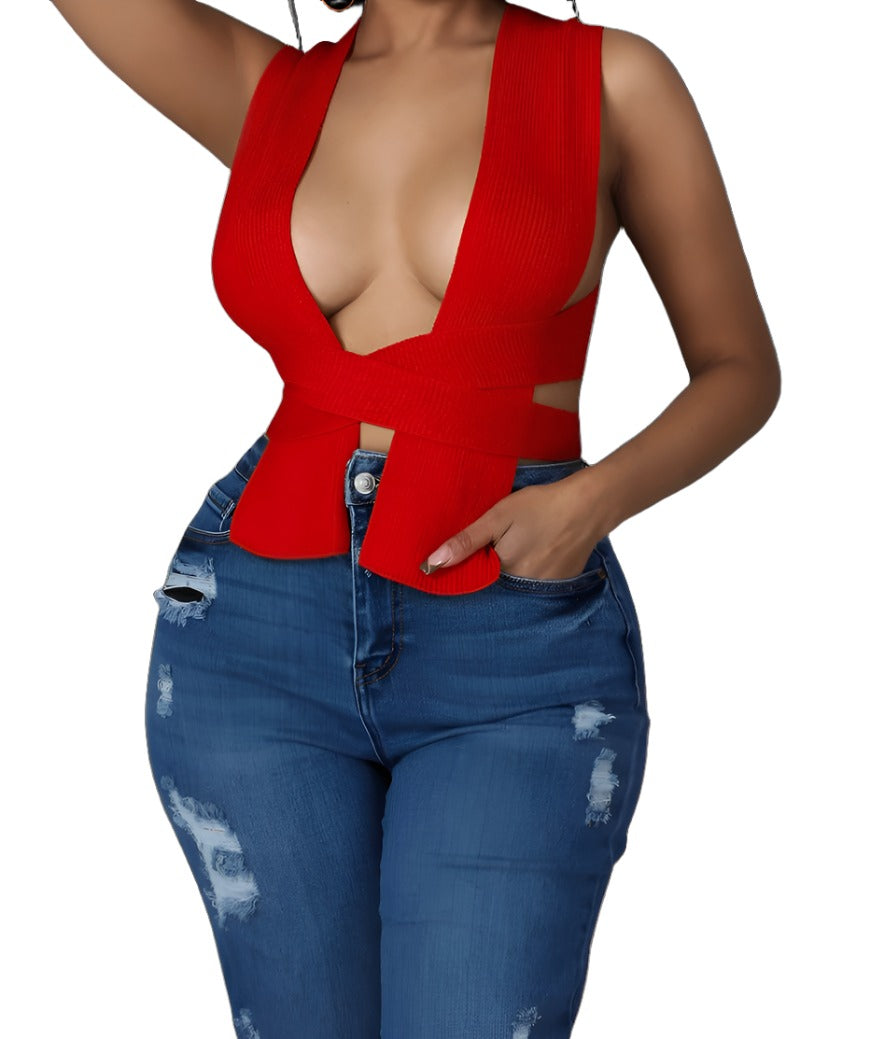 Woman wearing a red deep V-neck sleeveless knit crop top with a wrapped waist design, styled with distressed high-waisted blue jeans.