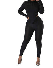 Woman wearing a sleek black full-length jumpsuit with long sleeves, side cutouts, and a sculpted corset-style bodice.