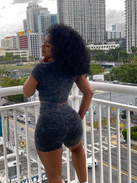 Woman wearing a black acid wash two-piece set with a fitted crop top and high-waisted biker shorts.