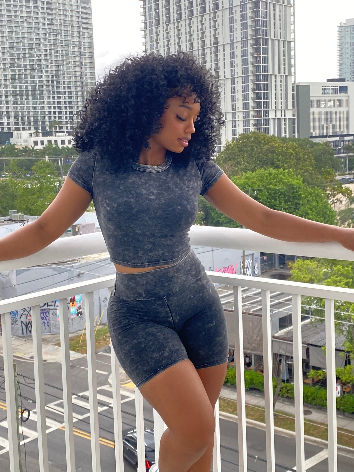 Woman wearing a black acid wash two-piece set with a fitted crop top and high-waisted biker shorts.