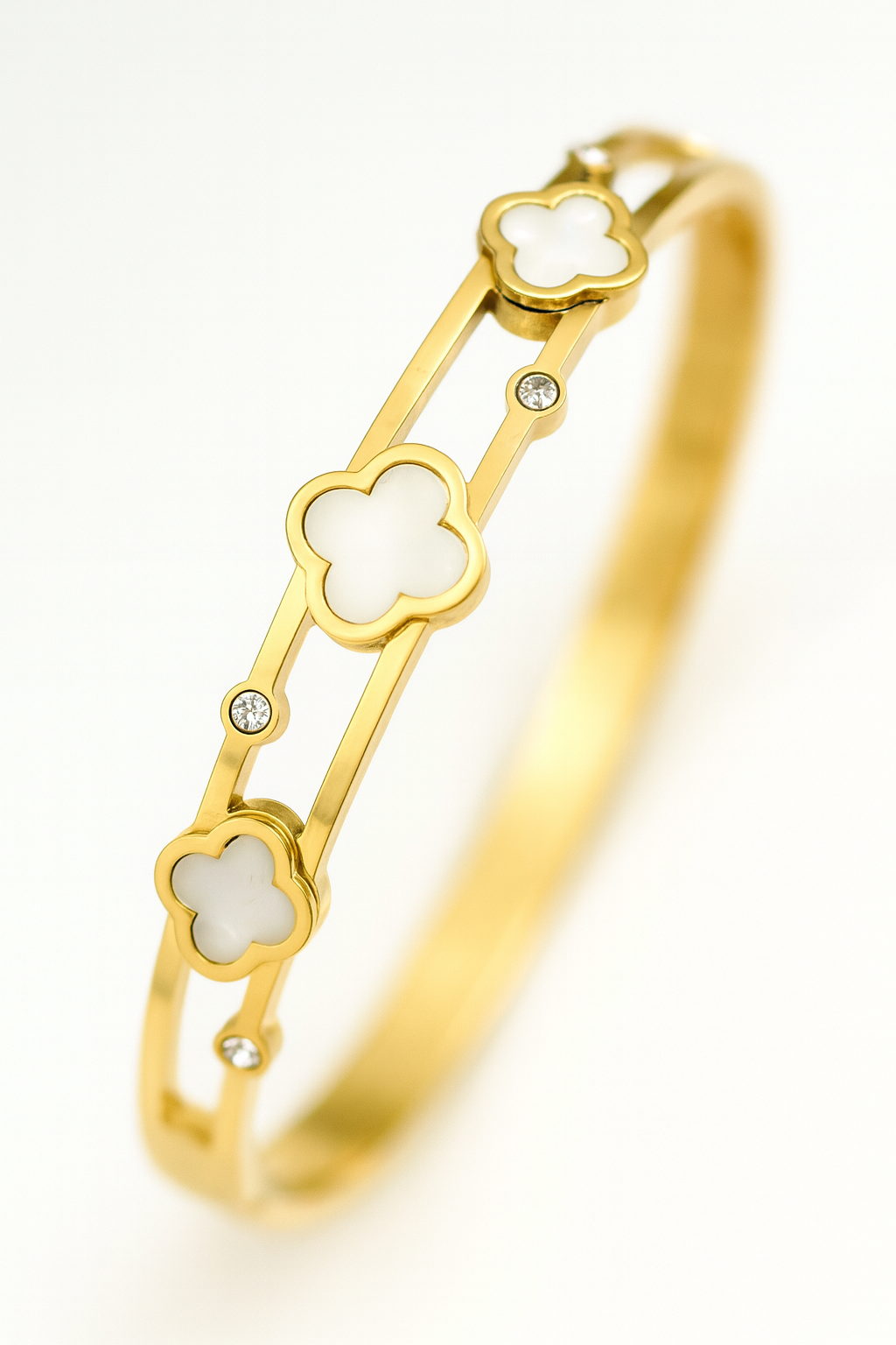 Gold bracelet with clover-shaped links on a white background