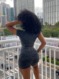Woman wearing a black acid wash two-piece set with a fitted crop top and high-waisted biker shorts.
