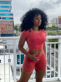 Woman wearing a red acid wash two-piece set featuring a fitted crop top and high-waisted biker shorts.