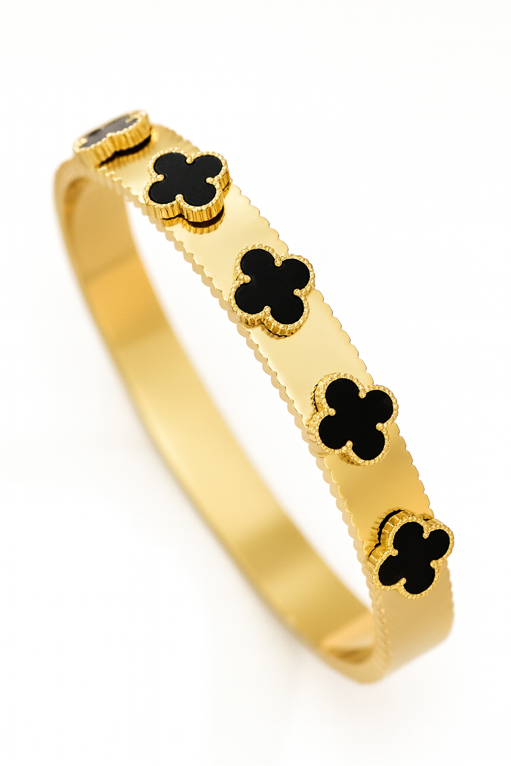 Gold bangle with black clover-shaped stones on a white background