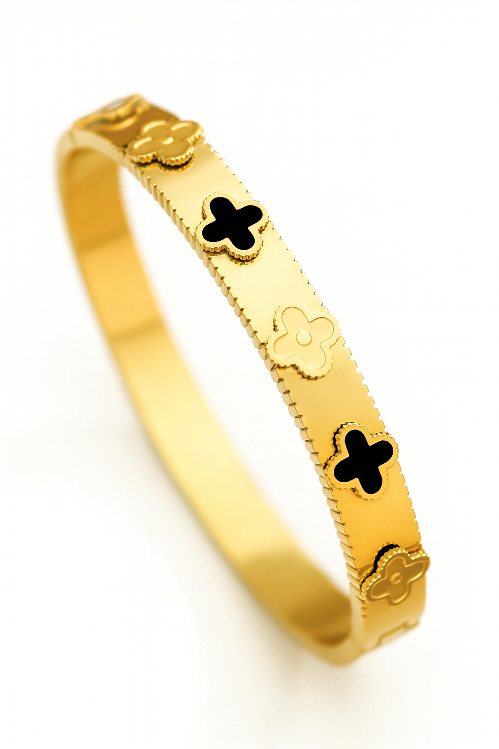 Gold bracelet with black flower designs on a white background