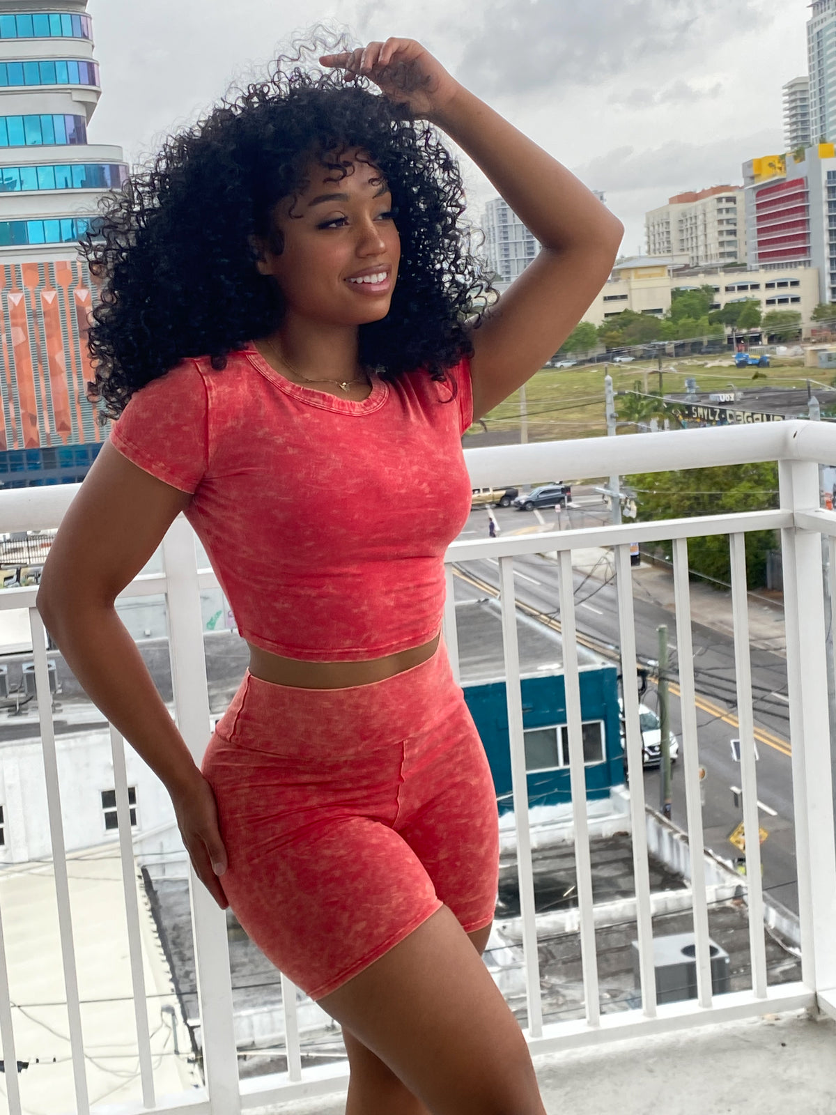 Woman wearing a red acid wash two-piece set featuring a fitted crop top and high-waisted biker shorts.