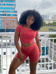 Woman wearing a red acid wash two-piece set featuring a fitted crop top and high-waisted biker shorts.