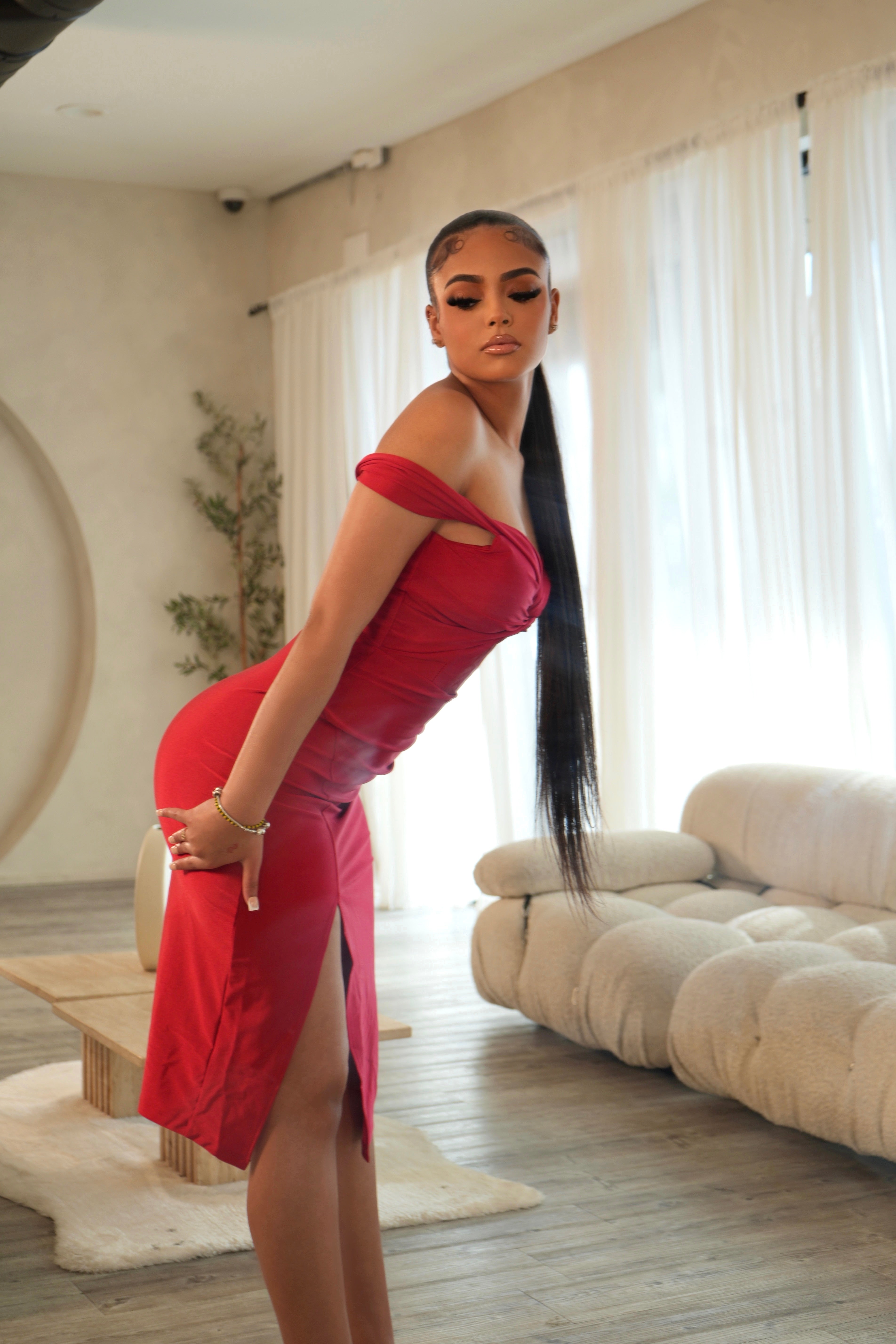 Woman in a red dress posing in a modern living room.