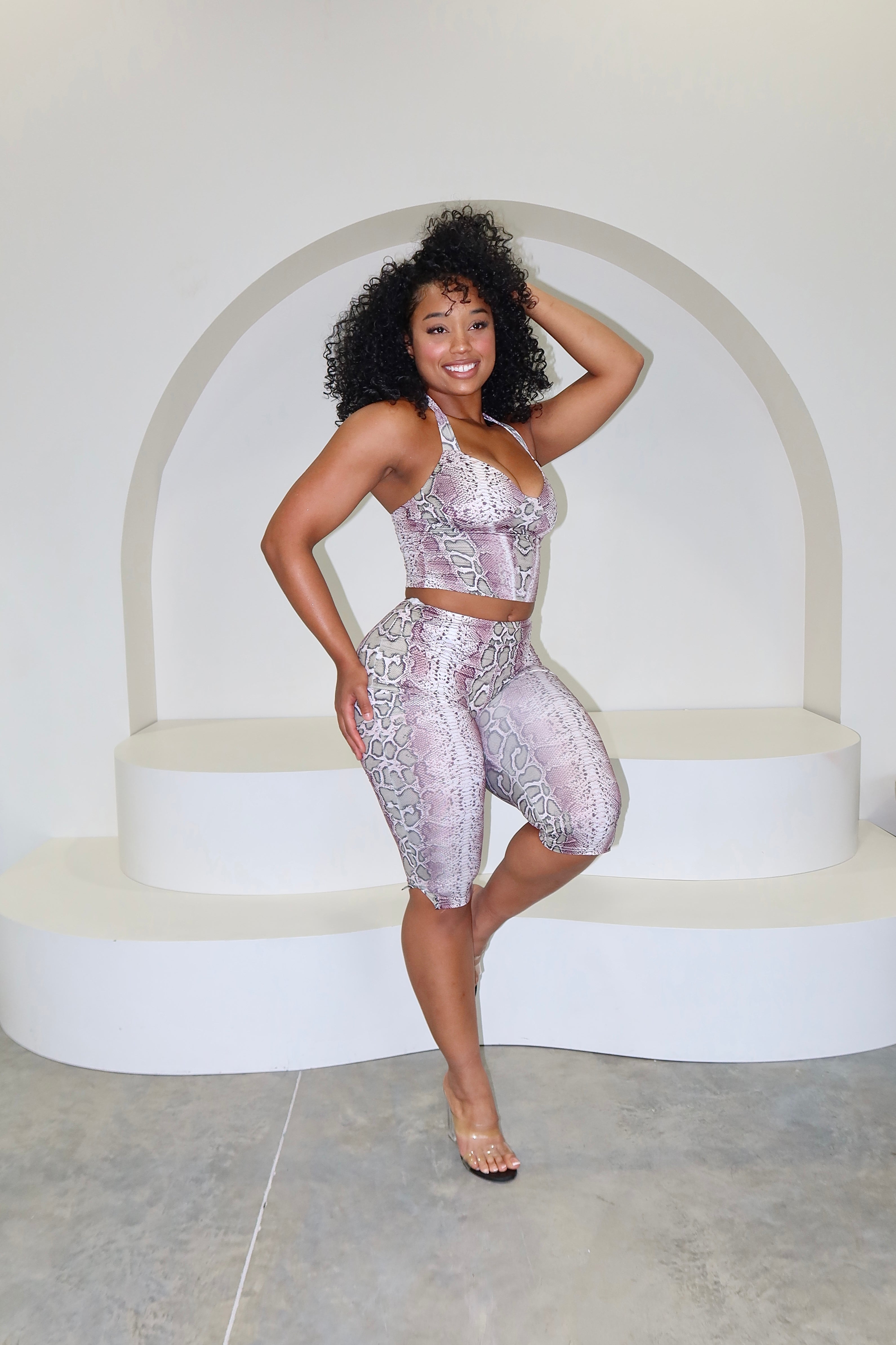 Woman in a matching top and shorts set posing on a white platform.