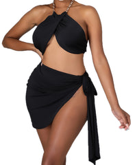 Woman wearing a black two-piece swimwear set featuring a twisted halter bikini top with chain straps and a high-slit side-tie mini sarong-style swim skirt.
