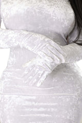 Close-up of a white crushed velvet bodycon dress featuring built-in gloves, showing the soft texture and glove detail with arms crossed at the waist.