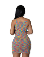 Woman wearing a multicolor sleeveless bodycon mini dress with circular cutouts along the front, secured by small ring details, in a rainbow knit pattern.